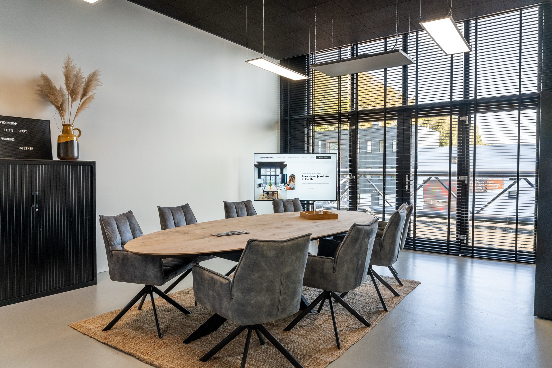 Flexkantoor L — grote ovale vergadertafel met acht stoelen en scherm