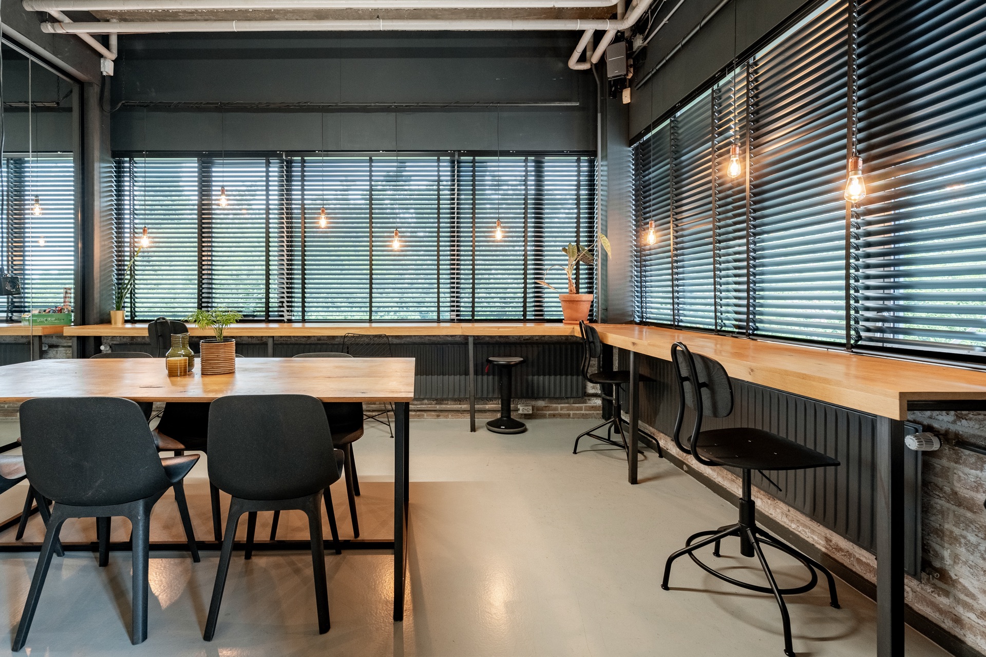 Flexkantoor M — werktafels met zwarte stoelen langs grote ramen