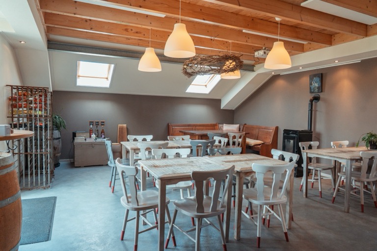 Proeflokaal binnen met tafels en stoelen onder houten balken