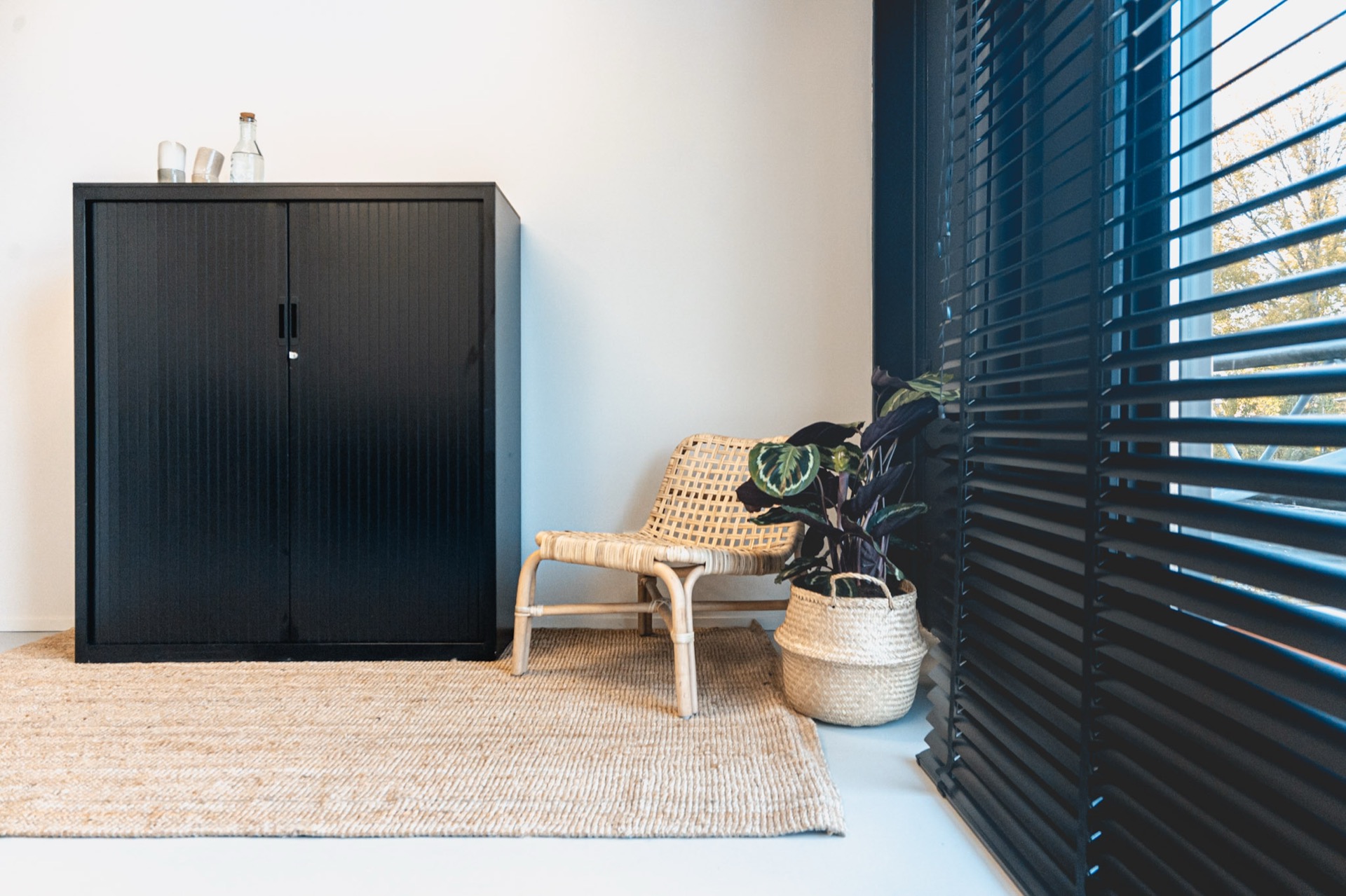 Zithoek met rotan stoel, plant en jute vloerkleed in het M-kantoor